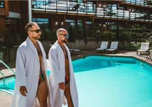 two men are standing next to a swimming pool at Brentwood Bay Resort & Spa in Brentwood Bay