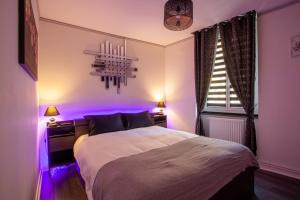 Un dormitorio con una cama con luces moradas. en L’Effusion en Bourg-en-Bresse