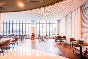 een restaurant met tafels en stoelen en grote ramen bij Hotel STAYON in Geoje 