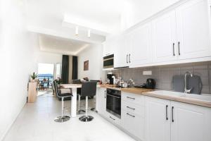 a kitchen with white cabinets and a table and chairs at Giannis sea-view apartment in Katávolos