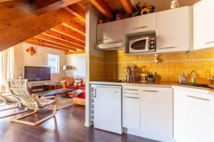 a kitchen with white cabinets and a living room at Appartement style chalet à Saint Lary Soulan. in Saint-Lary-Soulan