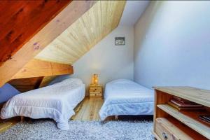 1 dormitorio en el ático con 2 camas y techo de madera en Appartement style chalet à Saint Lary Soulan., en Saint-Lary-Soulan
