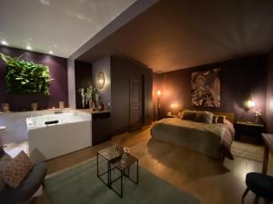 ein Schlafzimmer mit einem Bett und einer Badewanne in einem Zimmer in der Unterkunft La Planque - Chambres avec Jacuzzi in Fleury-en-Bière