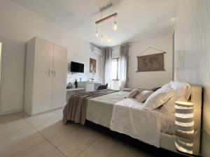 BARI ROOMS Suite Station في باري: غرفة نوم بيضاء مع سرير ومطبخ