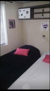 a bedroom with a black and white bed with pink pillows at Mobilhomme bungalow 6 personnes villeneuve loubet marina baie des anges in Villeneuve-Loubet