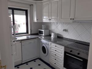a white kitchen with a washer and a microwave at Clube Meia Praia in Lagos