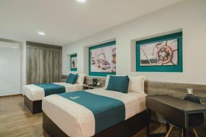 a hotel room with two beds and a desk at Real Naviero Hotel Ejecutivo in Manzanillo