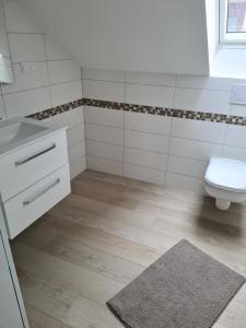 a white bathroom with a toilet and a sink at Ferienwohnung Ohanna Goslar in Goslar