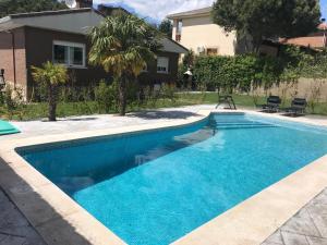 a swimming pool with blue water in front of a house at Chale a 25 minutos de Madrid cerca de Somosierra in El Casar de Talamanca