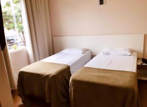 two beds in a hotel room with a window at Hotel Belvedere Araras - By UP Hotel - Fácil Acesso Hospital São Leopoldo e Faculdades in Araras