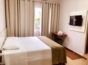 ein Hotelzimmer mit einem Bett und einem TV in der Unterkunft Hotel Belvedere Araras - By UP Hotel - Fácil Acesso Hospital São Leopoldo e Faculdades in Araras
