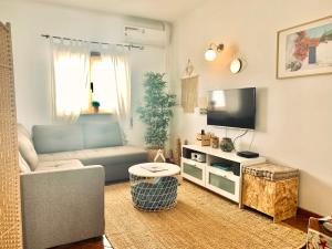 ein Wohnzimmer mit einem Sofa und einem Flachbild-TV in der Unterkunft Apartment Praia Arrifana with BALCONY and SEA VIEW in Aljezur