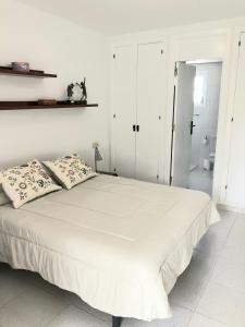 a white bedroom with a large bed with two pillows at Beach Apartment Minerva in Port d'Alcudia