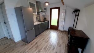 a kitchen with a refrigerator and a wooden floor at Le Pré Fleuri à Guillestre - Appartements neufs classés Meublés de Tourisme 3 étoiles- Climatisés- Parking privatif in Guillestre