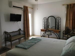 ein Schlafzimmer mit einem Bett und zwei Stühlen und einem Fernseher in der Unterkunft Luxury Villa Panorama Beach in El-Alamein