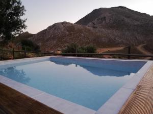 a swimming pool with a mountain in the background at Wooden House at the Mountain-private in Paránimfoi