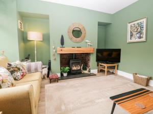 a living room with a fireplace and a tv at Walker's Cottage in Windermere
