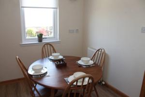 uma mesa de jantar em madeira com cadeiras e uma janela em BELL ROCK VIEW ARBROATH em Angus