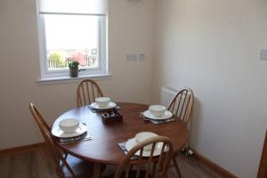 a wooden dining room table with chairs and a window at BELL ROCK VIEW ARBROATH in Angus