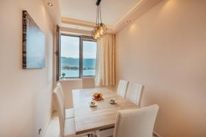 una sala da pranzo con tavolo, sedie e finestra di Apartmani Jelena a Tivat