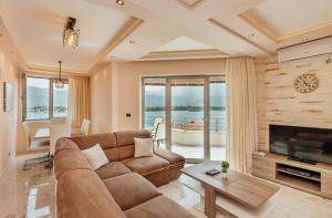 a living room with a couch and a tv and a table at Apartmani Jelena in Tivat