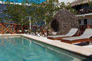 a swimming pool with two lounge chairs and a fountain at Sanyama Holbox in Holbox Island
