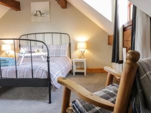 a bedroom with a bed and a chair at Cyffdy Cottage - Aran in Llanycil