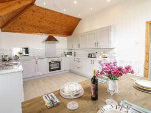 una cocina con armarios blancos y una mesa de madera con flores en Cyffdy Cottage - Tegid en Bala
