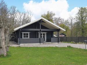 a black log cabin with a yard and grass at 8 person holiday home in Fr rup in Tårup