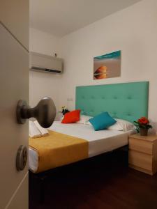 a bedroom with a bed with colorful pillows on it at Hotel Senza Pensieri Riccione in Riccione