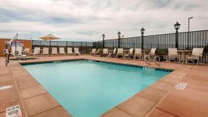 a large swimming pool with chairs and an umbrella at Best Western Plus Desert Poppy Inn in Lancaster