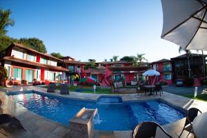 a swimming pool with chairs and umbrellas next to a house at Pousada dos Guardiões in Búzios