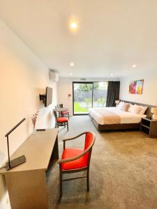 a hotel room with a bed and a desk and chairs at Carnmore Hagley Park in Christchurch
