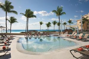 a pool at the beach with chairs and palm trees at Dreams Jade Resort & Spa - All Inclusive in Puerto Morelos