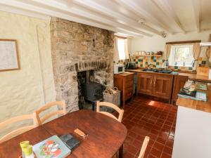 a kitchen with a table and a stone fireplace at Pwll Cottage in Carmarthen