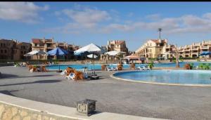 a swimming pool with chairs and umbrellas in a resort at Lazorde bay duplex chalet, North coast in El Alamein