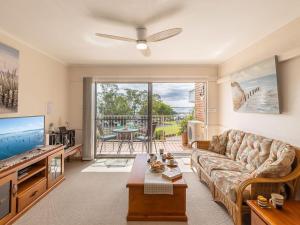 ein Wohnzimmer mit einem Sofa und einem Flachbild-TV in der Unterkunft Teramby Court, 10,104 Magnus Street - Unit in Nelson Bay CBD, with water views, air con and wi-fi in Nelson Bay