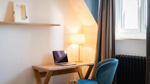 a room with a desk with a laptop and a chair at Hotel Stachus in Munich