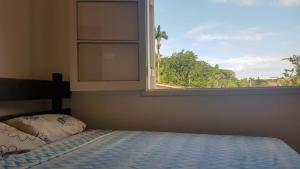 a bedroom with a bed and a window at Ombak Guest House in Ubatuba