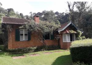 a small red brick house with a green window at Chalé aconchegante no Vale Encantado Bay window in Campos do Jordão