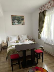 een slaapkamer met een bed en een tafel met stoelen bij Gizella vendégház in Odorheiu Secuiesc