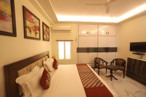 - une chambre avec un lit, une chaise et une télévision dans l'établissement Mandakini villa, à New Delhi