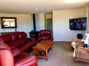 a living room with a red leather couch and chairs at Stunning 360-degree views in Twizel