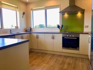 a kitchen with white cabinets and a green wall at Stunning 360-degree views in Twizel