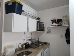 ポルト・デ・ガリーニャスにあるFlat Manawa A03の白いキャビネットとシンクのあるキッチン