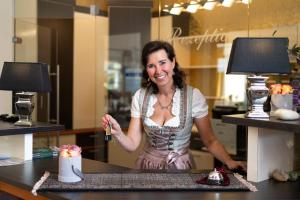 a woman standing behind a counter with a table with cakes at Hotel Garni Pölzl in Deutschlandsberg