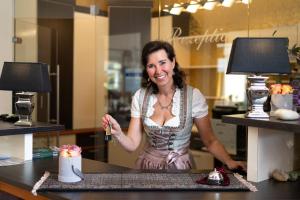 Eine Frau steht hinter einer Theke mit einem Tisch und Kuchen. in der Unterkunft Hotel Garni Pölzl in Deutschlandsberg