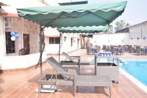 a patio with chairs and a pool with a green umbrella at Hotel JMD International Purnea in Pūrnia