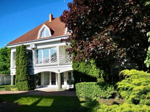 a large white house with a balcony and bushes at Győrfi Apartmanház Zamárdi in Zamárdi