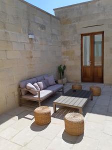 a patio with a couch and a table and chairs at Corte Kalìnora in Martano